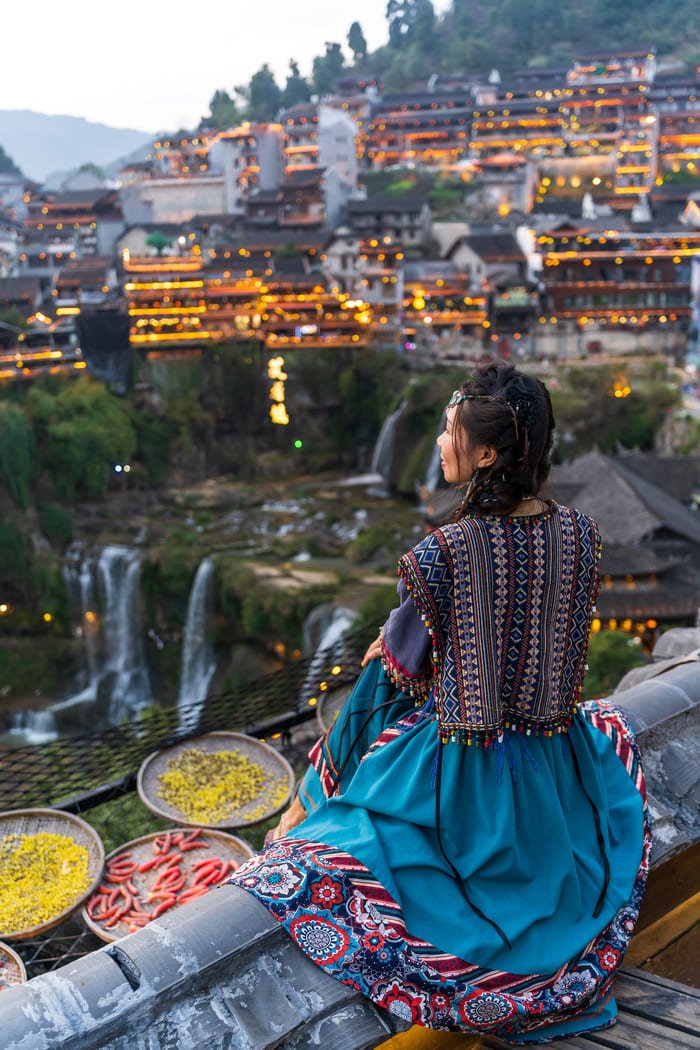 una persona observando el atardecerconun traje tipico en ciudad-lijiang
